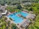 Aerial view of a luxurious swimming pool area with pergolas, palm trees, and ample seating for relaxation at 307 Heron Point Way, Deland, FL 32724