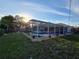 Backyard view of screened pool, fire pit and lush landscaping at sunset at 3209 S Dorchester Dr, Deltona, FL 32738