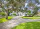 Charming house with manicured lawn, mature shade trees, and a circular driveway creating a welcoming curb appeal at 369 Caddie Dr, Debary, FL 32713