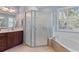 Bathroom with a glass shower enclosure, bathtub, and vanity with a sink, all brightly lit at 376 Chelsea Place Ave, Ormond Beach, FL 32174