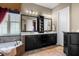 Well-lit bathroom featuring a double vanity with dark cabinetry, a soaking tub, and neutral tile flooring at 3955 Equine Cv, Lake Mary, FL 32746