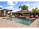 Beautiful pool area featuring a bar, water fountain, red cushioned lounge chairs and lush tropical landscaping at 3955 Equine Cv, Lake Mary, FL 32746