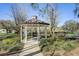 A white gazebo with a brown roof is surrounded by shrubbery and trees in the neighborhood at 406 Ravenshill Way, Deland, FL 32724