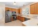 Well-lit kitchen with stainless steel appliances, tiled floor, and light wooden cabinets at 406 Ravenshill Way, Deland, FL 32724