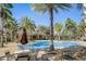 Community pool surrounded by palm trees, lounge chairs, and tables at 406 Ravenshill Way, Deland, FL 32724