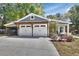 Attached two-car garage featuring white doors, stylish wooden pergola, ample parking, and garden bed at 427 E Church St, Deland, FL 32724