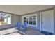 Inviting covered porch featuring wood-look floors, natural light, and two comfortable blue chairs at 437 Merrimac Dr, Port Orange, FL 32127