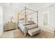 Elegant main bedroom with a four-poster bed, neutral tones, and an ensuite bathroom with a glass shower at 464 Tropics Ave, Daytona Beach, FL 32124