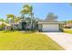 Beautiful single-story home with lush green lawn, palm trees, and a brick-paved driveway leading to a two-car garage at 6 Greenvale Dr, Ormond Beach, FL 32174