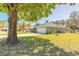Inviting green home with mature trees and a brick-paved driveway leading to a two-car garage, set against a clear blue sky at 6 Greenvale Dr, Ormond Beach, FL 32174