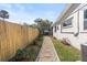 Backyard featuring a stone walkway, a wooden fence, and well-maintained landscaping with various plants and flowers at 617 S Flamingo Dr, Holly Hill, FL 32117