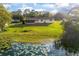 A large, grassy backyard gently slopes to the lake with lush vegetation and a serene atmosphere, perfect for relaxation at 902 Cloverleaf Blvd, Deltona, FL 32725