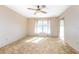 A bedroom with neutral walls, a ceiling fan, a window with curtains, and brown carpeting at 902 Cloverleaf Blvd, Deltona, FL 32725