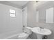 Clean, well-lit bathroom features a tub with shower, neutral tile and a modern sink with pedestal at 1020 Alladin Dr, Deltona, FL 32725