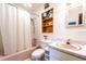 Well-lit bathroom with a pink bathtub, white tiling, and a decorative shelf for towels and toiletries at 1199 Galgano Ave, Deltona, FL 32725