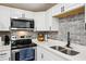 Modern kitchen with stainless steel appliances, quartz countertops, and gray tile backsplash at 1265 Aquarius Ave, Deland, FL 32724