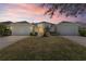 Exterior view of two homes each with a two-car garage and well-maintained lawns under a colorful sky at 1422 Carlow Cir, Ormond Beach, FL 32174