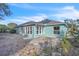 Back exterior view of the blue home featuring a brick patio, sun room, and solar panels at 1877 N Merrick Dr # 0, Deltona, FL 32738