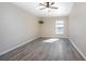 Bright bedroom showcasing wood-look floors, a ceiling fan, and a window overlooking the backyard at 201 Williams Ave, Orange City, FL 32763