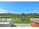 Manicured lawn with lake view, swing set, and hot tub create a relaxing backyard oasis at 214 Caryota Ct, New Smyrna Beach, FL 32168
