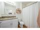 Well-lit bathroom with granite countertop, vanity, and shower with a white curtain, and decorative shelf at 214 Caryota Ct, New Smyrna Beach, FL 32168