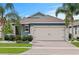 Charming home featuring stone accents, a brick driveway, and beautiful landscaping with palm trees at 214 Caryota Ct, New Smyrna Beach, FL 32168