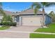 The home features a two-car garage, attractive landscaping, and a brick-paved driveway at 214 Caryota Ct, New Smyrna Beach, FL 32168