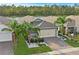 Charming home featuring a two-car garage, stone accents, tropical landscaping, and a well manicured lawn at 214 Caryota Ct, New Smyrna Beach, FL 32168
