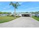 Single-story home boasts carport, lush lawn, and mature palm trees at 24919 Drive No 1, Astor, FL 32102