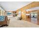 Bright and open living room featuring wood paneling, plush carpeting, and a view of the kitchen at 24919 Drive No 1, Astor, FL 32102