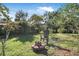 Green backyard with fire pit and Adirondack chair under a blue sky and mature trees at 3228 Unity Tree Dr, Edgewater, FL 32141