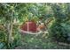 Backyard area with shady hammock, wooden shed, mature trees and green ferns at 3228 Unity Tree Dr, Edgewater, FL 32141