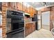 Compact kitchen features retro appliances, brick accent wall, rustic wood cabinets, and tile floors at 354 Georgetown Dr, Daytona Beach, FL 32118