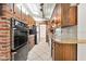 Well-lit kitchen with stainless steel appliances, rustic wood cabinets, brick accent wall, and tile floors at 354 Georgetown Dr, Daytona Beach, FL 32118