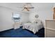 Cozy bedroom with blue carpet, ceiling fan, and large window offering a peaceful retreat at 3620 Cardinal Blvd # 80, Daytona Beach, FL 32118