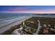 Expansive aerial view showcasing a luxurious oceanfront estate with private beach access, coastline and nearby city skyline at 4911 S Atlantic Ave, Ponce Inlet, FL 32127