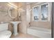 Bright bathroom featuring a tub, separate shower, pedestal sink, and natural light at 4911 S Atlantic Ave, Ponce Inlet, FL 32127