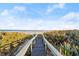 Charming wooden boardwalk leading to a serene beach with gentle waves and lush dune vegetation, perfect for relaxation at 4911 S Atlantic Ave, Ponce Inlet, FL 32127