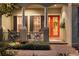 Inviting front porch with an orange door, adorned with seasonal wreath and decor at 509 Victoria Hills Dr, Deland, FL 32724