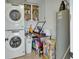 Laundry room with stacked washer/dryer, storage cabinets, and cleaning supplies at 525 E Wisconsin Ave, Orange City, FL 32763