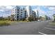 Charming condo exterior featuring a parking lot, green lawns, and tropical palm trees at 5300 S Atlantic Ave # 17-303, New Smyrna Beach, FL 32169