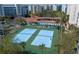 A view of two well-maintained tennis courts with the pool, clubhouse, and condos in the background at 5300 S Atlantic Ave # 17-303, New Smyrna Beach, FL 32169