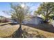 Fenced backyard with large trees, a lawn, and screened-in porch and a house with grey siding at 723 Pelican Ct, Kissimmee, FL 34759