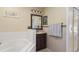 Bright bathroom featuring a tub, vanity with dark wood cabinets, and neutral tile flooring at 723 Pelican Ct, Kissimmee, FL 34759
