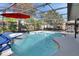 A screened-in pool features an attached spa, bright blue water, a gray deck, and a red umbrella at 725 Briarcrest Dr, Orange City, FL 32763