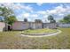 View of the home's backyard featuring a beige wall, grass and an overgrown flowerbed at 852 Derbyshire Rd, Daytona Beach, FL 32117