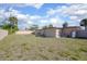 View of the home's backyard featuring a beige wall, grass and blue skies with fluffy clouds at 852 Derbyshire Rd, Daytona Beach, FL 32117