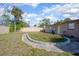 View of the home's backyard featuring a beige wall, grass and an overgrown flowerbed at 852 Derbyshire Rd, Daytona Beach, FL 32117