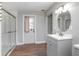 Bathroom featuring a glass shower and modern vanity with a round mirror and a door to the exterior at 852 Derbyshire Rd, Daytona Beach, FL 32117
