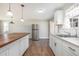 Updated kitchen with butcher block island, stainless fridge, and bright, stylish pendant lights at 852 Derbyshire Rd, Daytona Beach, FL 32117